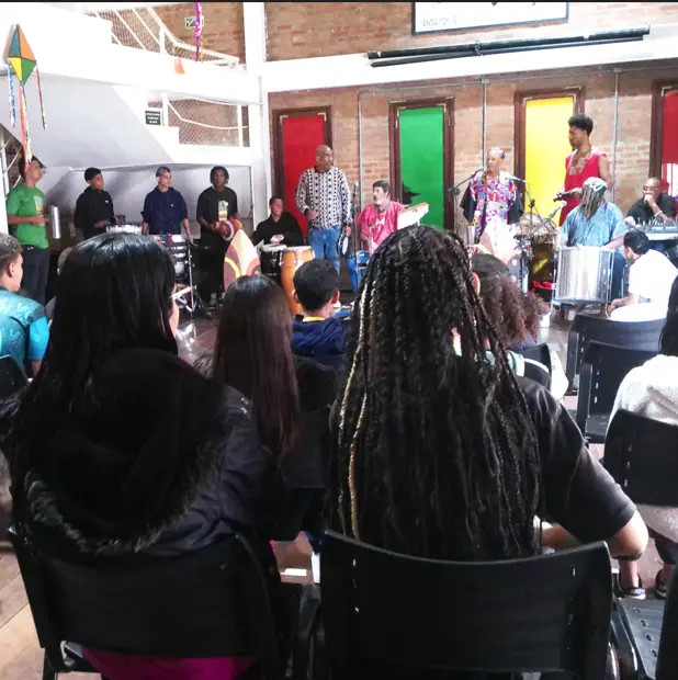 Flateia de jovens e crianças assistindo ao espetáculo musical.