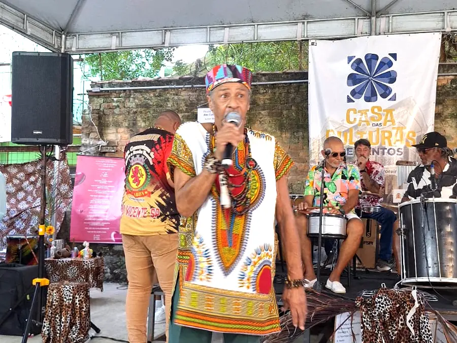 Artista se apresenta com grupo musical ao fundo.