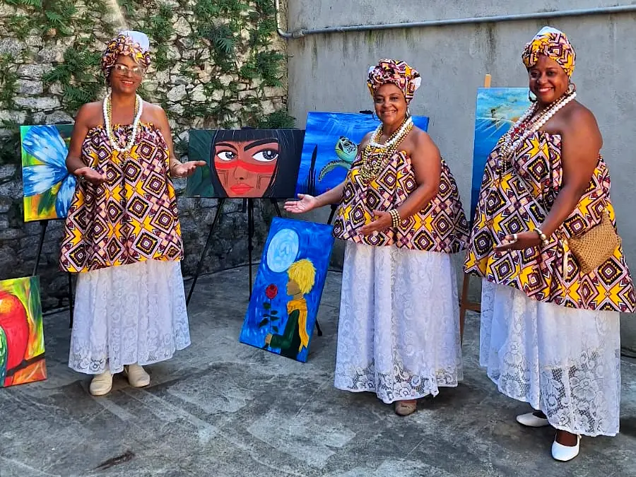 Três mulheres vestidas de baianas tradicionais do carnaval.